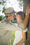 Cute couple leaning against tree in the park