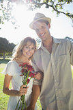 Attractive blonde holding roses standing with partner smiling at camera