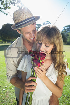 Attractive blonde smeling roses standing with partner