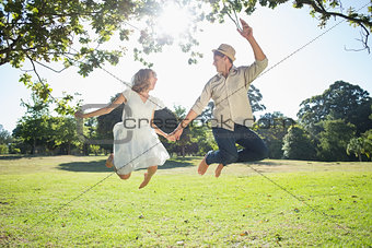 Cute couple jumping in the park together holding hands