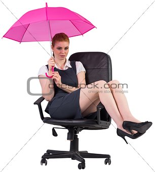 Businesswoman holding umbrella sitting on swivel chair