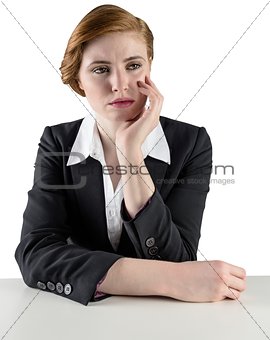 Thinking redhead businesswoman sitting at desk