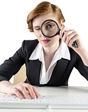 Redhead businesswoman looking through magnifying glass