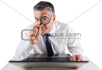 Mature businessman examining with magnifying glass