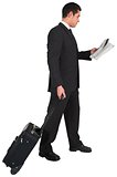 Businessman pulling his suitcase holding newspaper