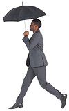 Businessman walking and holding umbrella