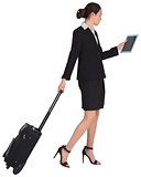Businesswoman pulling her suitcase holding tablet