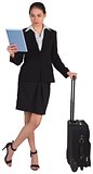 Businesswoman leaning on her suitcase holding tablet pc