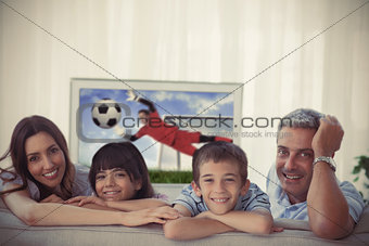 Family smiling at the camera with world cup showing on television