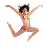 Fit girl in bikini leaping and smiling at camera