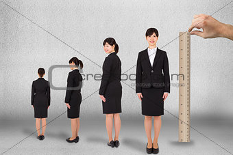 Composite image of hand measuring businesswoman with ruler