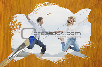 Composite image of couple jumping on the beach