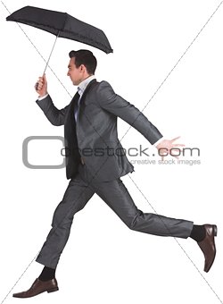 Businessman jumping holding an umbrella