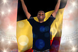 Composite image of excited football fan in black cheering holding belgium flag