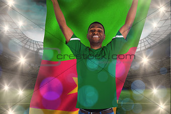 Composite image of cheering football fan in green jersey holding cameroon flag