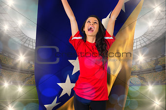 Composite image of cheering football fan in red holding bosnian flag