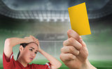 Composite image of hand holding up yellow card to fan