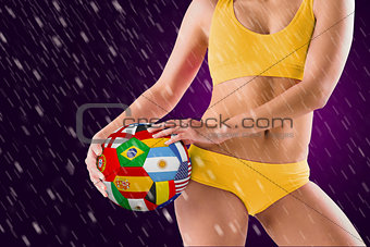 Composite image of fit girl in yellow bikini holding flag football