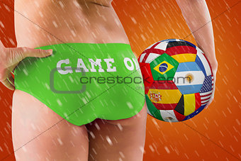 Composite image of fit girl in green bikini holding flag football