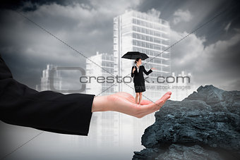 Composite image of young businesswoman holding umbrella in hand