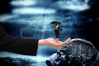 Composite image of young businesswoman holding umbrella in large hand