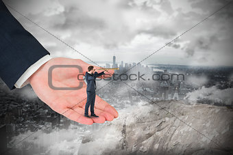 Composite image of businessman looking through telescope in large hand