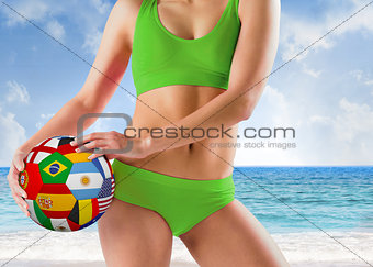 Composite image of fit girl in green bikini holding flag ball
