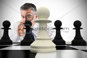 Composite image of focused businessman with magnifying glass