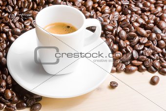 white cup with espresso coffee near coffee beans