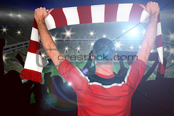 Composite image of football player holding striped scarf
