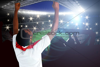 Composite image of excited handsome football fan cheering