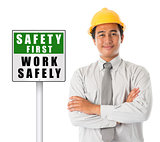Asian male wearing yellow hardhat with safety first sign board.