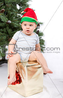 Baby boy sitting on Christmas gift.