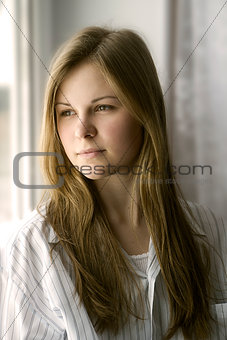 Portrait of a girl in a white shirt in the window