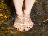 Dipping feet in water off a stone beach