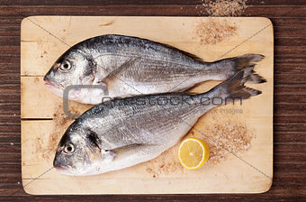 Two fish on wooding kitchen board.