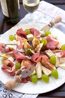 Appetizer with prosciutto, figs, cheese and grapes