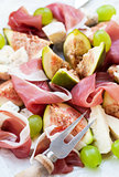 Appetizer with prosciutto, figs, cheese and grapes