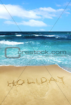 Holiday written in beach sand
