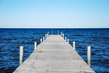 Low angle image of a wooden bath pier in blue water