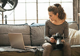 Young woman with modern dslr photo camera using laptop in loft a