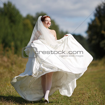 Happy caucasian bride walking field.