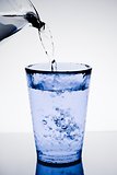 filling a blue glass with pure water and bubbles 