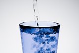 filling a blue glass with pure water and bubbles 