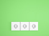Green wall with three european electric outlets.Conceptual.