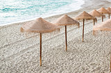 Straw parasols on empty beach. Nerja, Spain