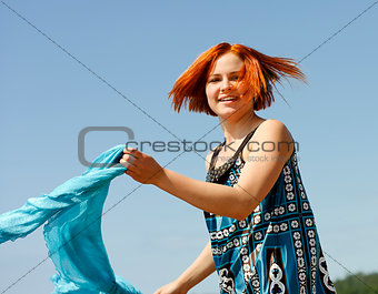 Portrait of a beautiful young woman outside running on the beach with a scarf