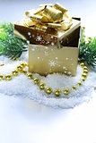 golden gift box with beautiful ribbon in the snow, christmas still life