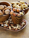 different kinds of nuts (almonds, walnuts, hazelnuts, peanuts) in a bowl on a wooden table