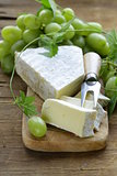 Soft brie cheese with sweet grapes on a wooden board